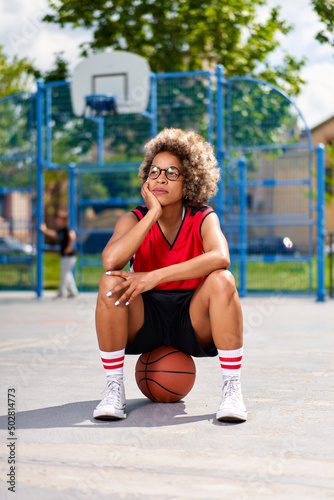 girl with afro hairstyle with a ball on a basketball court