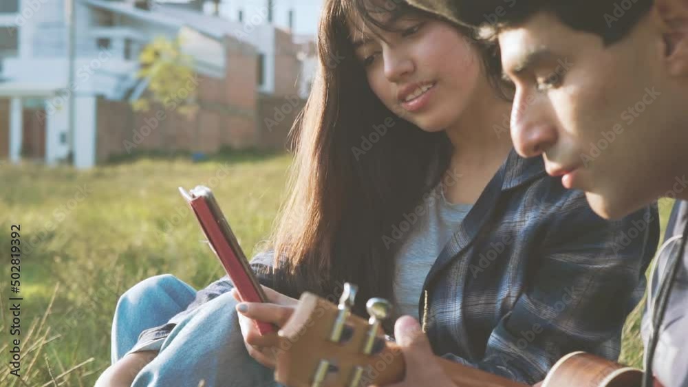 Mujer aprendiendo a tocar ukulele (Guitarra pequeña) en un parque al atardecer.