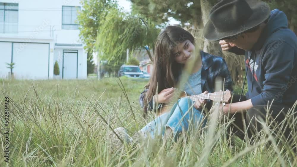 Mujer aprendiendo a tocar ukulele (Guitarra pequeña) en un parque al atardecer.