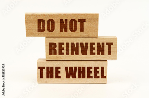 On a white surface are wooden blocks with the inscription - Do Not Reinvent The Wheel