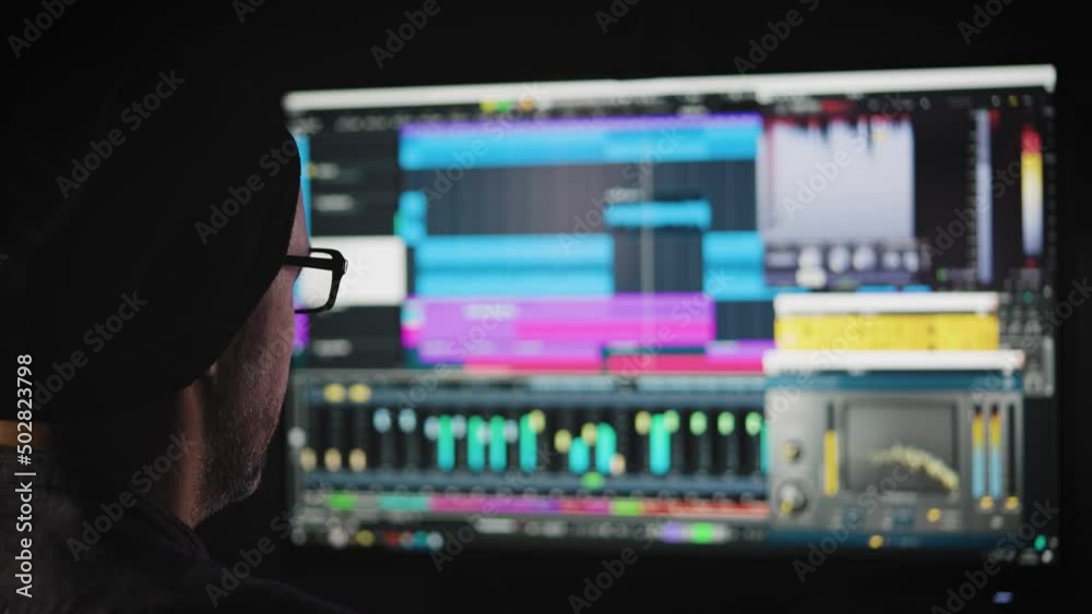 An experienced sound engineer mixes a music track in his home studio.