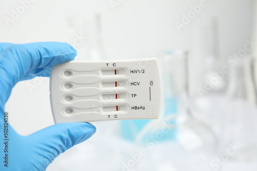 Doctor holding disposable express test for hepatitis indoors, closeup