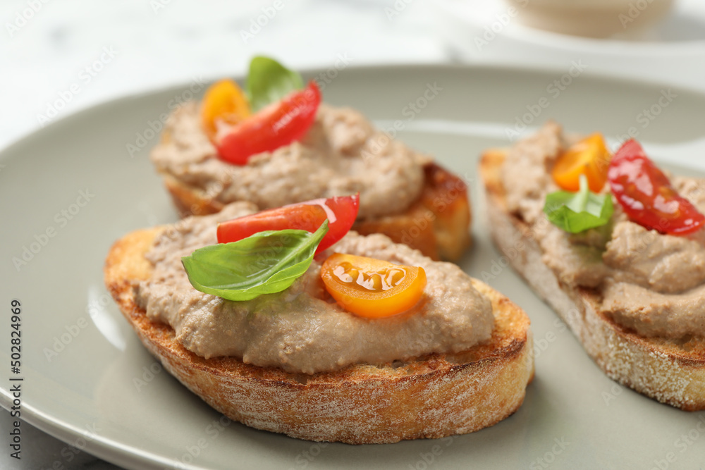 Slices of bread with delicious pate, tomatoes and basil on plate, closeup
