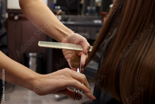 Professional hairdresser cutting woman's hair in salon, closeup