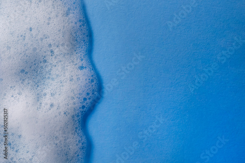 White foam on light blue background, top view. Space for text