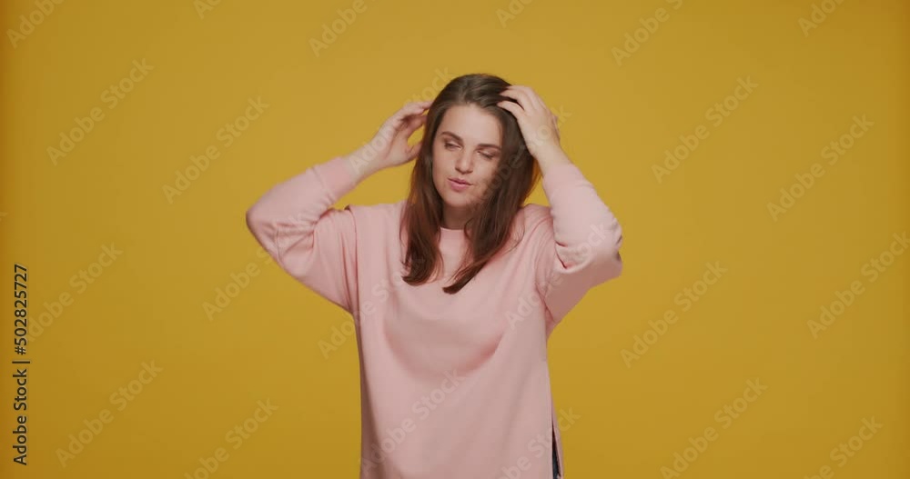 Young girl fix hairs, freshen her makeup, primping, preening up, preparing for dating on yellow studio background Young girl fix hairs, freshen her makeup, primping, preening up, preparing for dating on yellow studio background