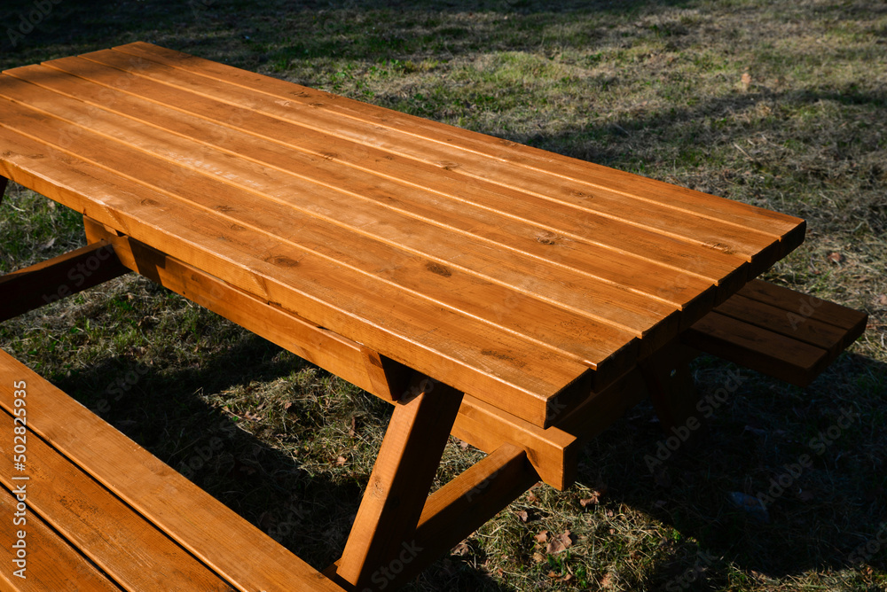 Empty wooden picnic table with benches in park on sunny day
