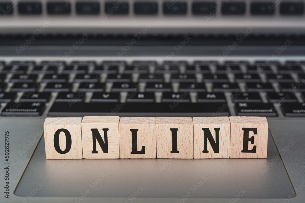Online text on wooden block with open laptop. Online text on wooden block with open laptop.