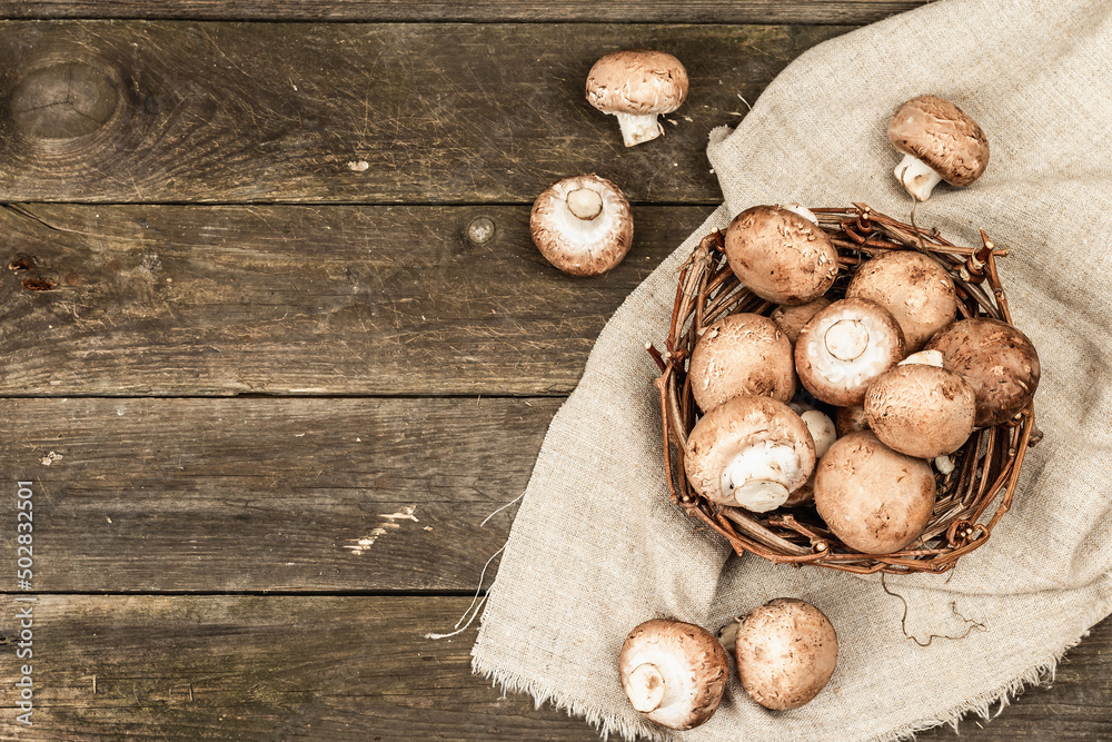 Fresh brown champignons in a wicker basket. Raw ingredients for cooking vegan food Fresh brown champignons in a wicker basket. Raw ingredients for cooking vegan food