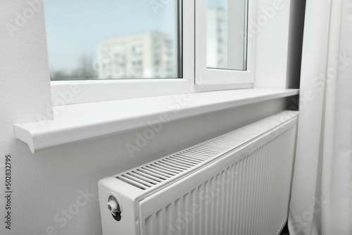 Modern radiator under window at home. Central heating system