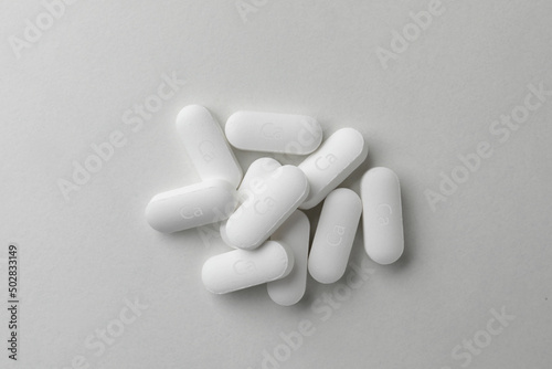 Pile of calcium supplement pills on light grey background, flat lay