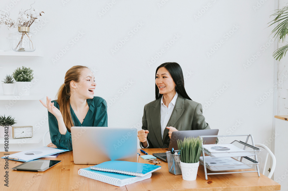 two young business women professionals in formal wear clothes work in modern office using laptop, tablet, brainstorm and search for solutions together, confident independent Asian girl solves problems two young business women professionals in formal wear clothes work in modern office using laptop, tablet, brainstorm and search for solutions together, confident independent Asian girl solves problems