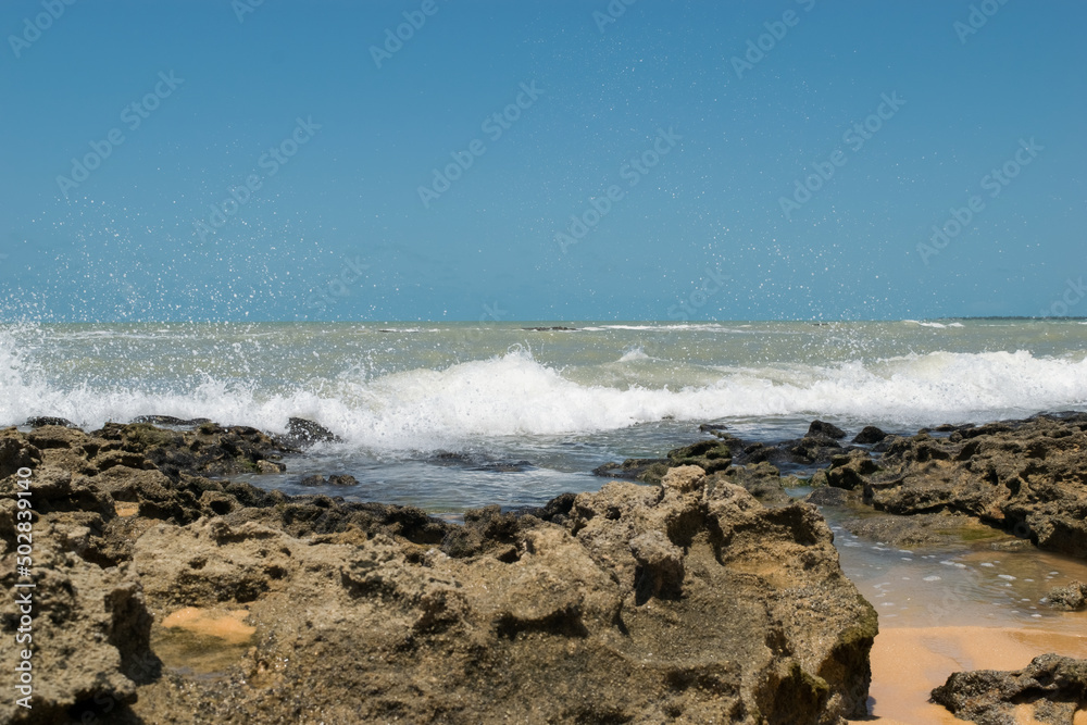 Linda praia com muitas pedras sendo banhadas pelas ondas, localizada em Cabrália na região de Porto Seguro, Bahia, Brasil.