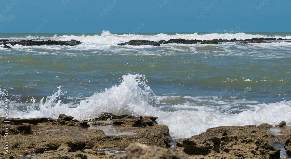 Linda praia com muitas pedras sendo banhadas pelas ondas, sob um lindo céu azul, localizada em Cabrália na região de Porto Seguro, Bahia, Brasil. Linda praia com muitas pedras sendo banhadas pelas ondas, sob um lindo céu azul, localizada em Cabrália na região de Porto Seguro, Bahia, Brasil.
