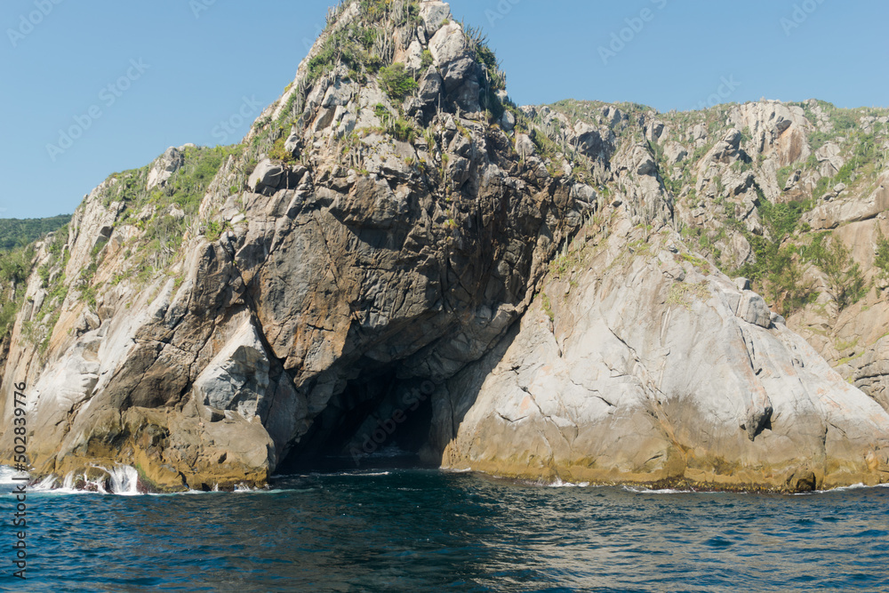 Montanha rochosa a beira do mar e com caverna no meio, localizada na região de Cabo Frio, Rio de Janeiro, Brasil.