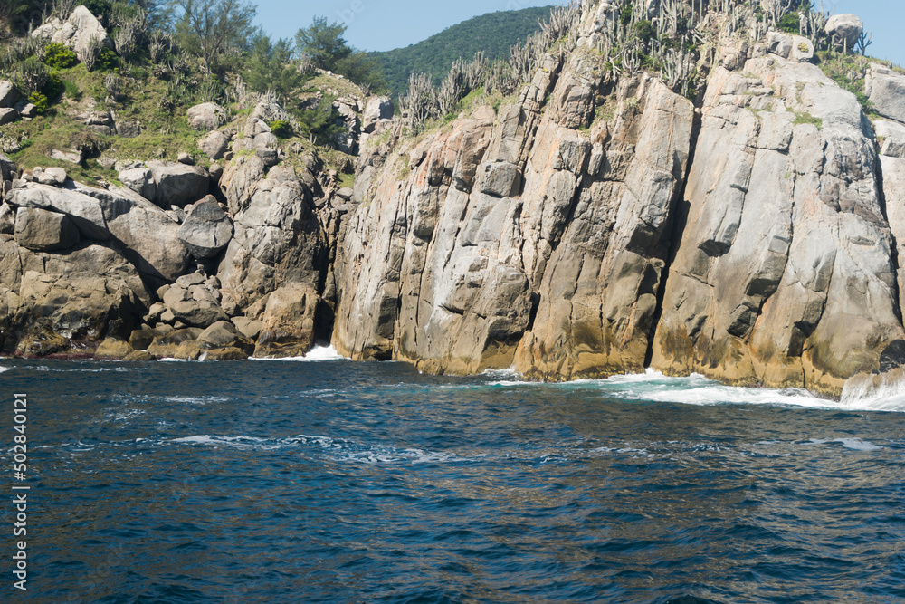 Pequena montanha rochosa a beira do mar e com caverna no meio, localizada na região de Cabo Frio, Rio de Janeiro, Brasil.