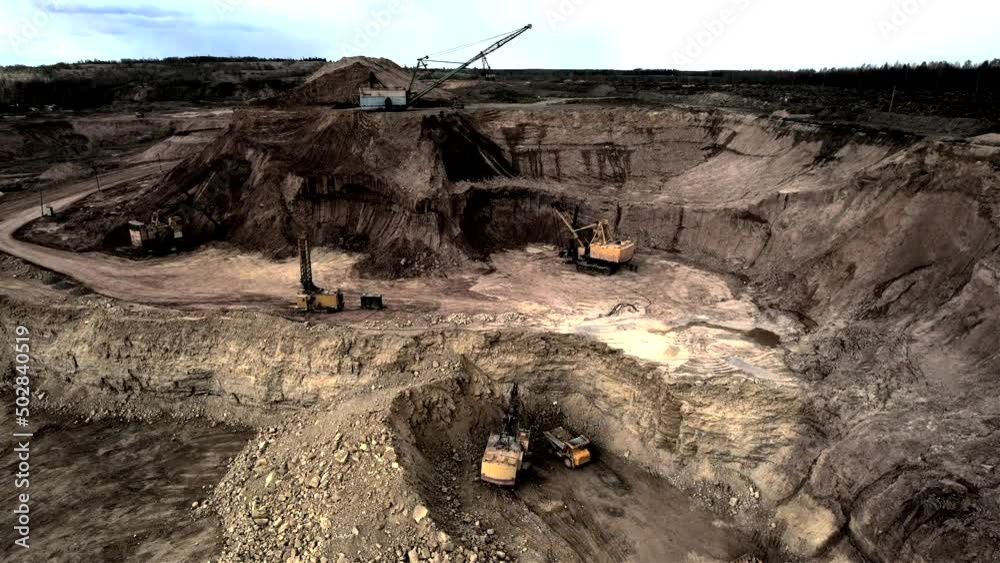 Mining excavator loading dolomite minerals in haul truck. Limestone mining in a dolomite quarry. Walking dragline excavator in an open pit. Mining truck transports limestone from opecast, drone view. Mining excavator loading dolomite minerals in haul truck. Limestone mining in a dolomite quarry. Walking dragline excavator in an open pit. Mining truck transports limestone from opecast, drone view.