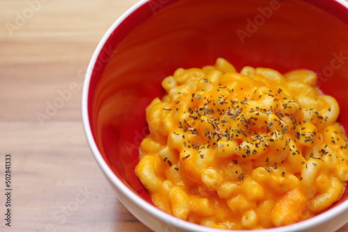 Macaroni cheese served in orange cup plates with Oregano garnish. photo