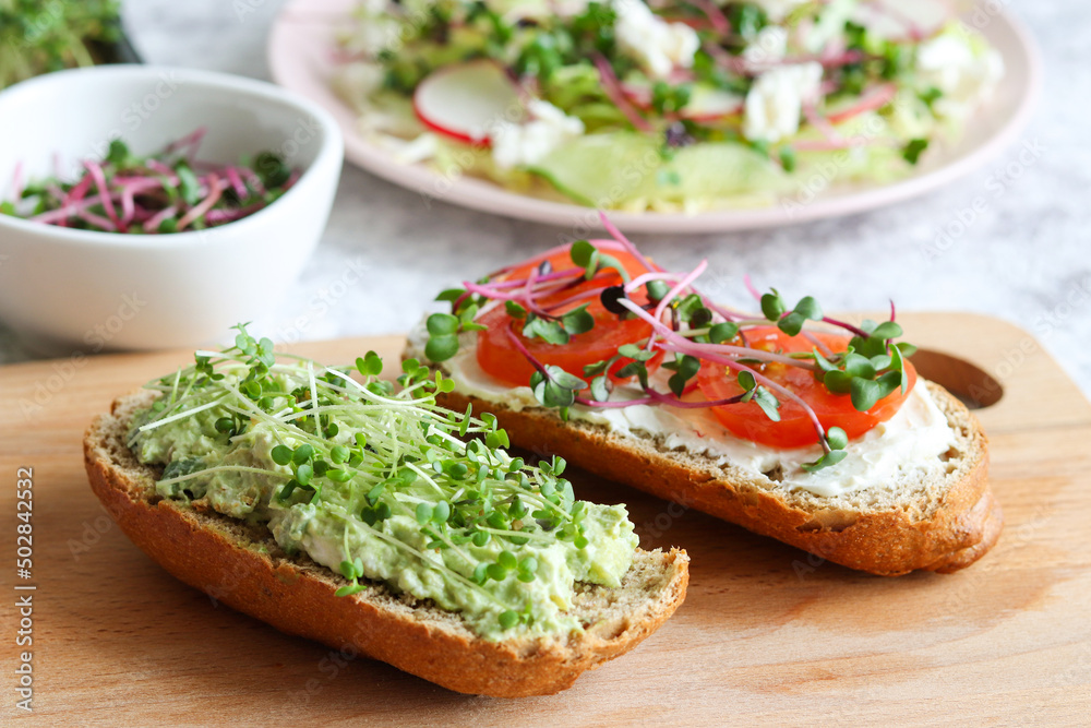 Delicious homemade bruschetta with avocado, tomatoes and microgreens for breakfast or snack. Healthy food. Selective focus Delicious homemade bruschetta with avocado, tomatoes and microgreens for breakfast or snack. Healthy food. Selective focus