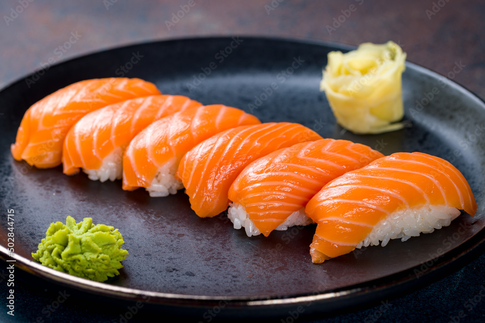 sushi salmon on a black plate on blue concrete table macro close up sushi salmon on a black plate on blue concrete table macro close up