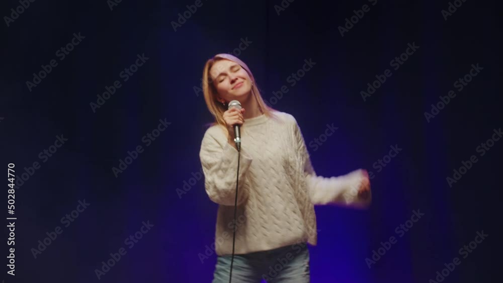 Karaoke cafe. Woman singer close-up. Female musician singing song on stage, using microphone. Musical performance, talent contest. Karaoke cafe. Woman singer close-up. Female musician singing song on stage, using microphone. Musical performance, talent contest.