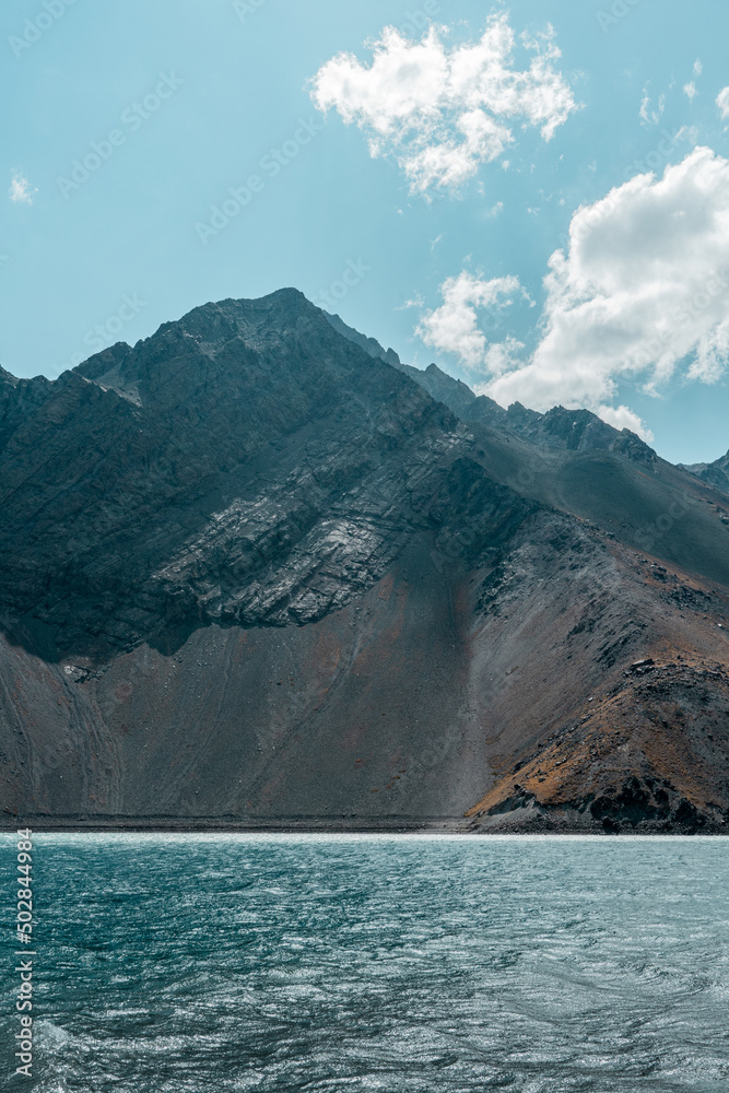 Fototapeta premium Vertical shot of turquoise water in the Embalse del Yeso reservoir with colored mountains in the background, Chile.