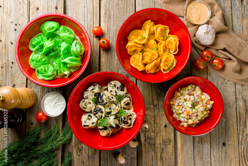 Dumplings with sour cream and herbs, green dumplings, orange dumplings, salad olivier top view on wooden table