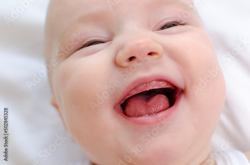 Baby smiling with a toothless mouth close-up. Infant laughing. Children healthcare photo