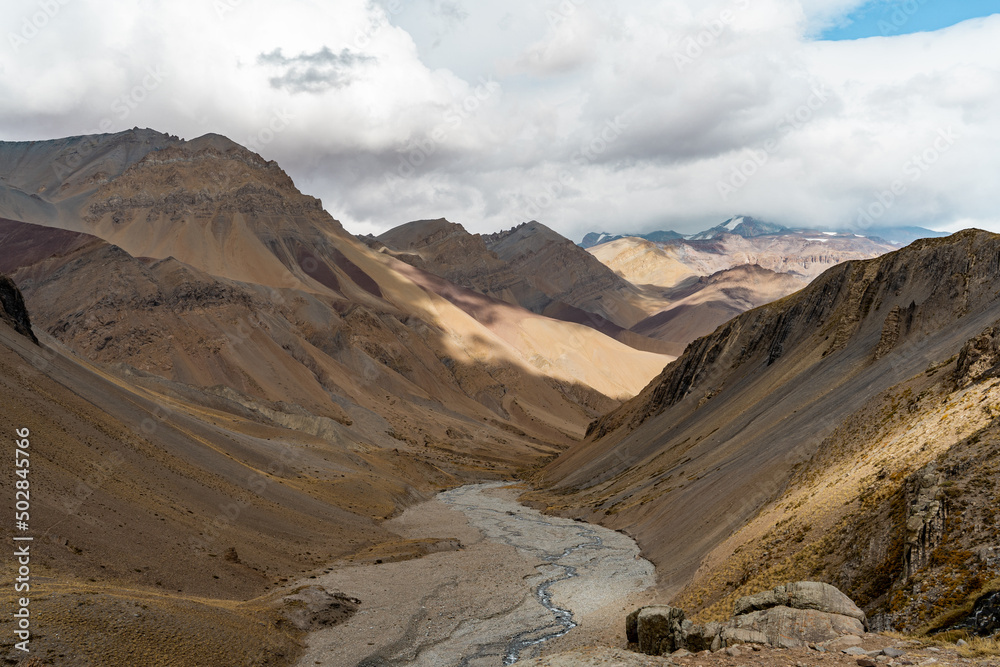 Fototapeta premium Horizontal shot of colorful mountain valley with a river on a cloudy day, Chile