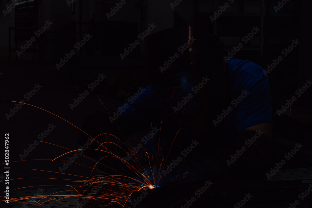 Professional Heavy Industry Welder Working Inside factory, Wears Helmet and Starts Welding. Selective Focus Professional Heavy Industry Welder Working Inside factory, Wears Helmet and Starts Welding. Selective Focus