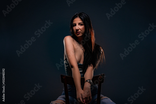 Sitting on the chair and posing in studio
