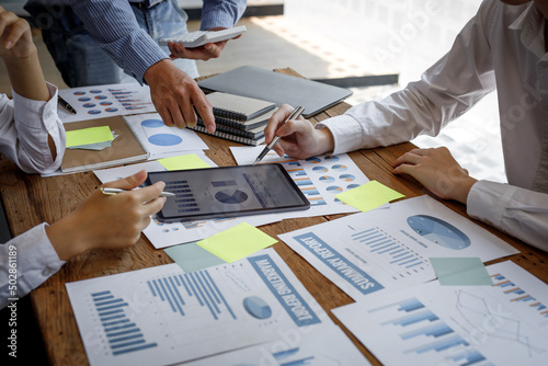 Financial analysts analyze business financial reports on a digital tablet planning investment project during a discussion at a meeting of corporate showing the results of their successful teamwork.