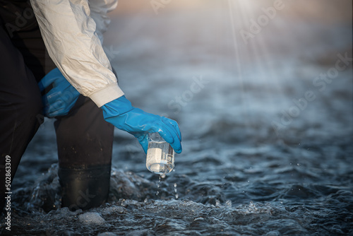 Researchers, scientists in protective clothing use water for analysis from polluted rivers.