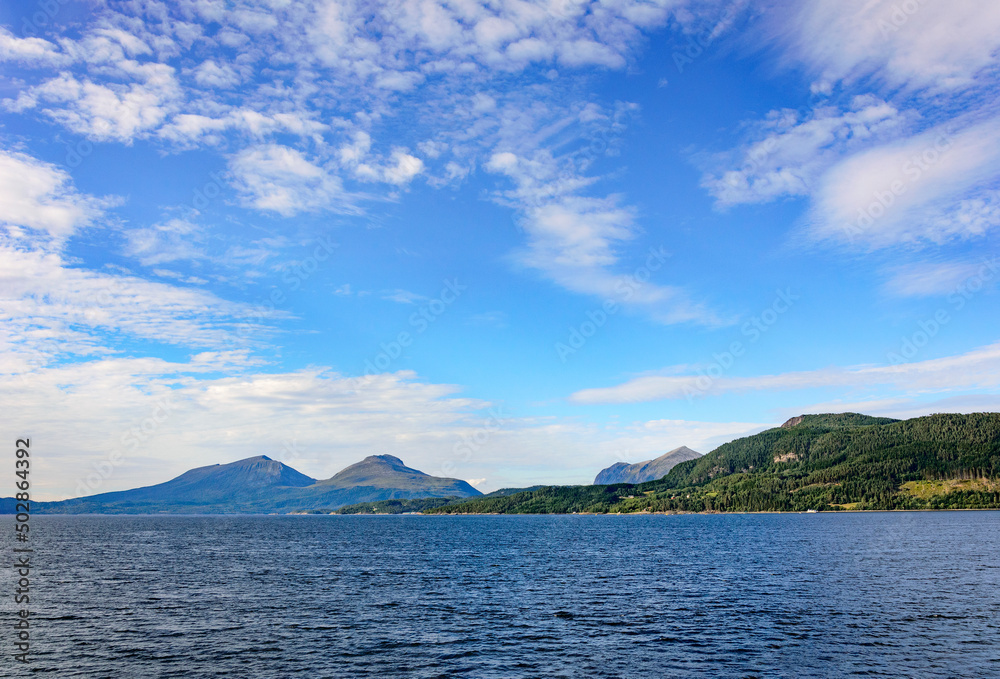view of the  Stangviksfjord in Norway. Light blue sky with white clouds, blue sea water, mountains on the horizon