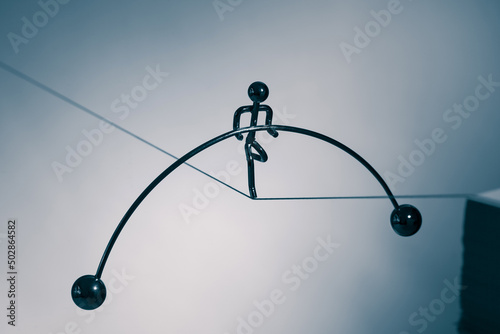 a little toy man with balance bar walking on a rope. photo