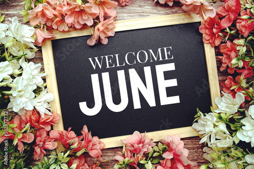 Welcome June typography text written on wooden blackboard with flower bouquet decorate on wooden background photo