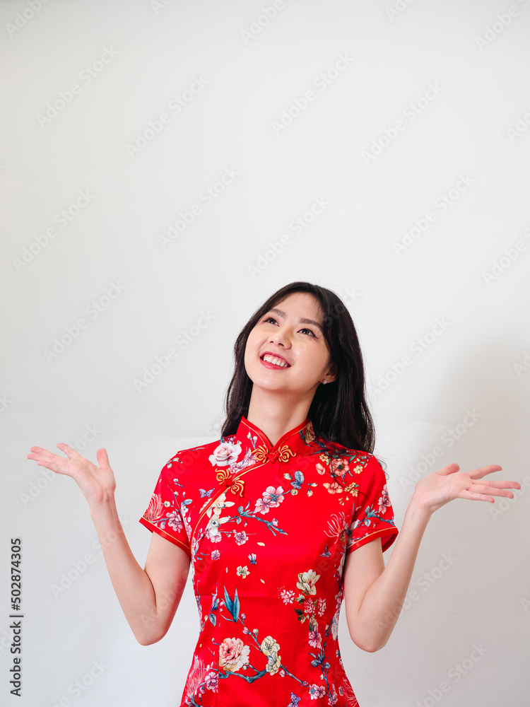 Portrait of young asian woman wearing traditional cheongsam qipao dress over isolated white background holding copyspace with two hands. Portrait of young asian woman wearing traditional cheongsam qipao dress over isolated white background holding copyspace with two hands.