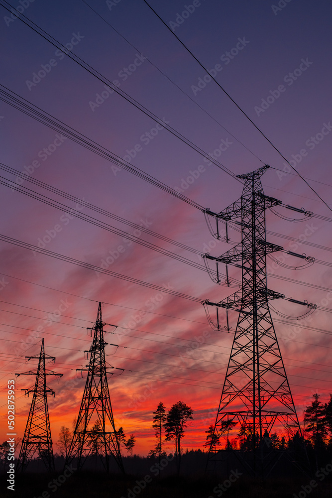 Electric pylons in the Estonian countryside in autumn during sunset. Dramatic sky in the background.