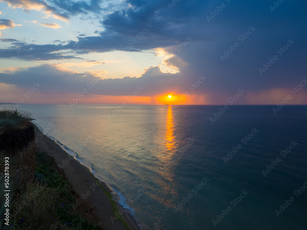Thunderstorm at sea at dusk. The Beauty of Sunrise waves. Seascape with dramatic cloudy sky and rising sun in Ukraine. Sanzhiyka, Odesa. Landscape with sea and steep coast