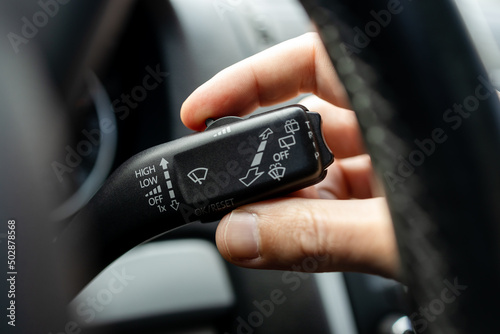 male person adjusting car wipers speed. car wiper switch handle macro close up. windshield wipers speed control wheel. car interior