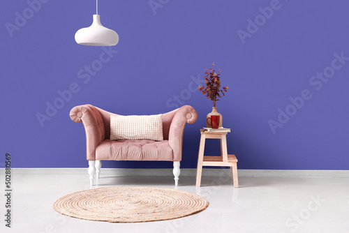 Interior of stylish living room with sofa near violet wall