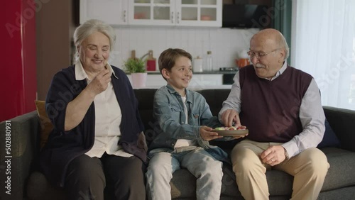 Little boy visiting his grandparents.Little boy eats colorful candies with his grandparents. Portrait of visiting the elderly.