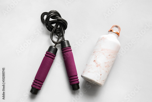 Bottle and skipping rope on white background