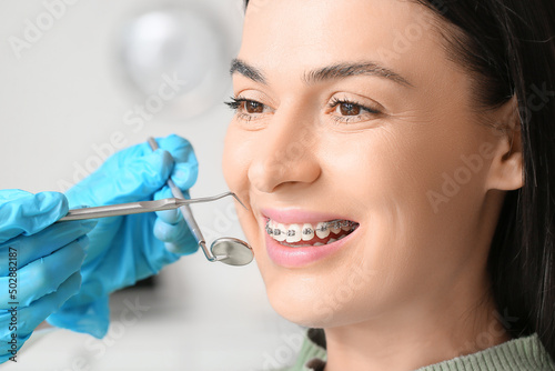 Woman with dental braces visiting dentist in clinic  closeup
