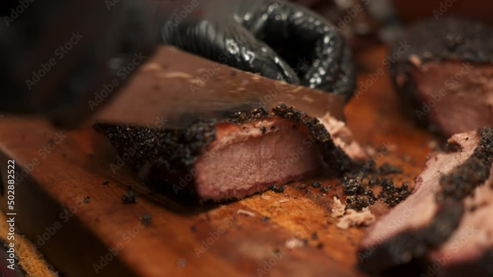 Chef slices tender moist lean Texas beef brisket with precision, Pitmaster cuts perfectly smoked barbecue brisket portions for plates, slow motion close up 4K