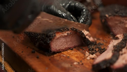 Chef slices tender moist lean Texas beef brisket with precision, Pitmaster cuts perfectly smoked barbecue brisket portions for plates, slow motion close up 4K