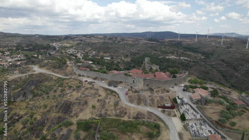 Aerial descending wide panoramic view of Sortelha village and wind turbines for eolic energy production in background. Portugal Aerial descending wide panoramic view of Sortelha village and wind turbines for eolic energy production in background. Portugal