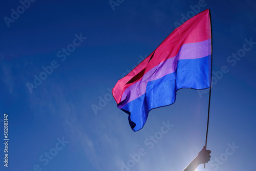 Bisexual flag fluttering in the wind over a blue sky.
