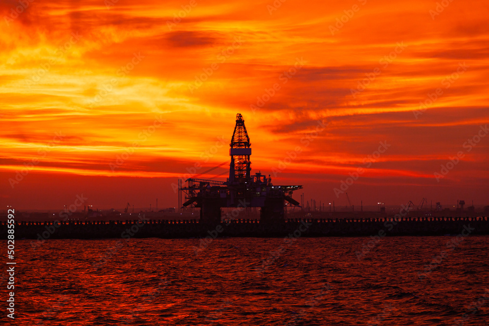 Offshore oil platform moored at the pier during a red sunset.