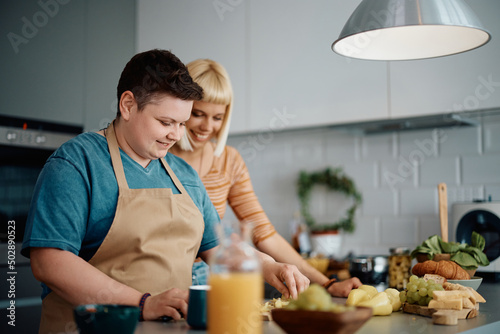Happy gay woman preparing food with her girlfriend in kitchen.